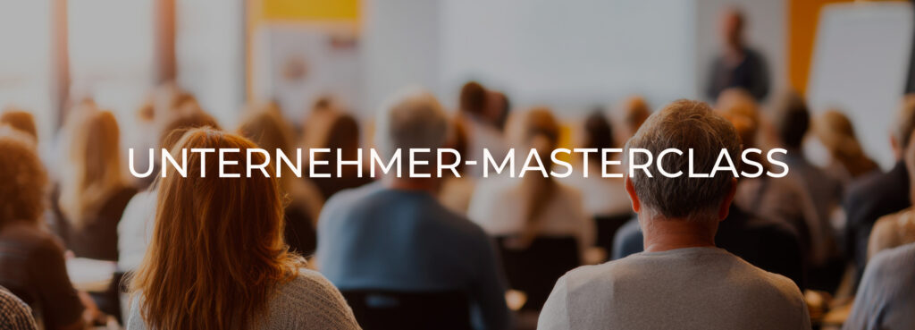 Audience seated in a conference room facing a speaker, with a bold title overlay reading 'UNTERNEHMER-MASTERCLASS' across the image.